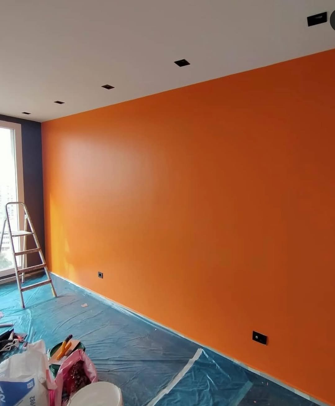Interior painting project with bright orange accent wall